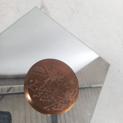 un petit miroir posé sur une table, avec une pièce de un penny dessus