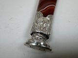 a silver spoon with a red handle on a white surface