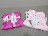 two pink pillows with tags on them sitting on a couch