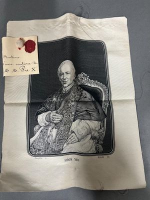 une vieille photo représentant un homme assis sur une chaise, avec un cachet de cire rouge