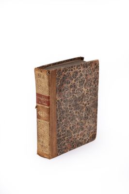 an old book sitting on top of a white table next to a white wall