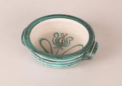 a green and white bowl sitting on top of a white table