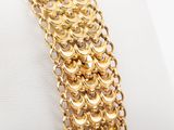 a close up of a gold chain bracelet on a white surface