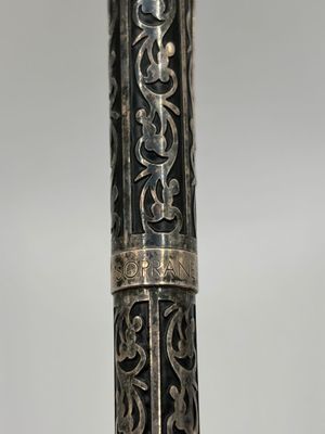 un vieux stylo en argent orné d'un motif en noir et blanc
