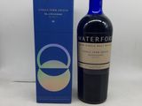 La bouteille de Waterford se trouve à côté de la boîte, sur la table.