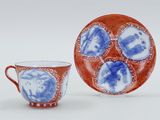 an orange and blue cup and saucer sitting next to each other on a white surface