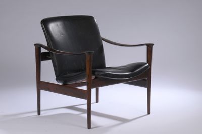 une image représentant un fauteuil en cuir noir posé sur un sol blanc
