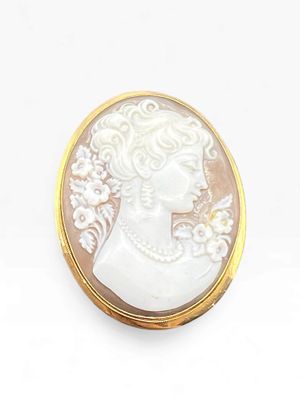 an image of a woman ' s profile is shown in a white and gold broochle
