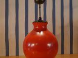 a red lamp that is on a wooden table