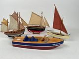 four small wooden boats with sails on a white surface