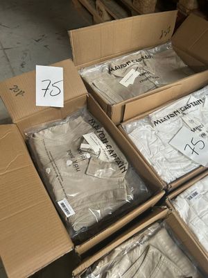 Plusieurs cartons de t-shirts blancs sont empilés les uns sur les autres