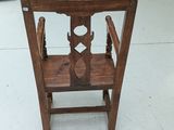 a wooden chair with a glass display case in the background