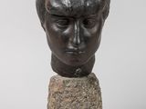 une tête d'homme en bronze posée sur un rocher