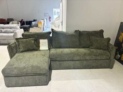 un canapé et un pouf dans une pièce où est accroché un tableau au mur