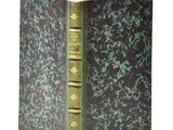 an old book with a green cover sitting on top of a white table