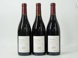 trois bouteilles de vin rouge sont alignées sur une surface blanche