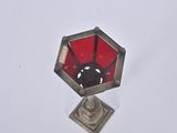 a red glass in the middle of a silver candle holder