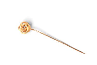 une broche en or ornée d'un nœud, posée sur un fond blanc