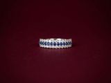 a white gold ring with blue sapphires and diamonds on a red background