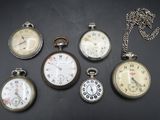Plusieurs modèles différents de montres de poche sont exposés sur un fond noir