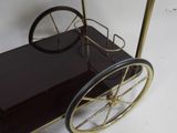 a black and gold bar cart with wheels on a white surface