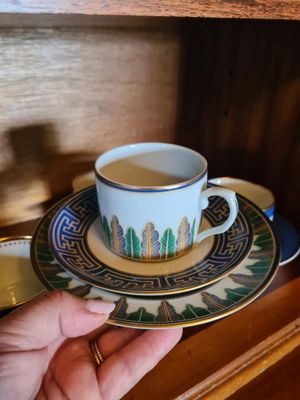 une personne tenant une tasse et une soucoupe posées sur une assiette