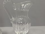 two glass pitchers sitting on a table next to each other