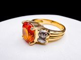 a close up of a gold ring with an orange stone