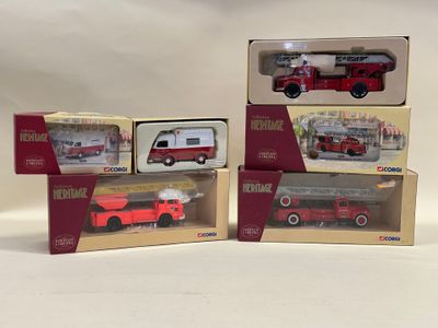 trois boîtes contenant des camions de pompiers miniatures, posées sur une surface blanche