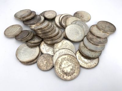 a pile of old silver coins on a white surface