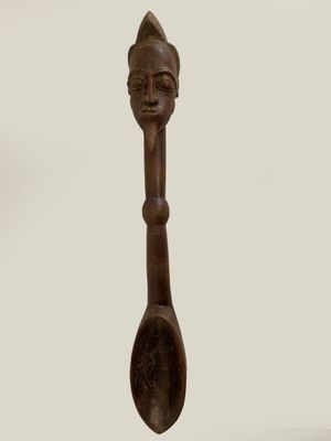 a wooden spoon with a face on it and a spoon in the shape of a spoon