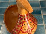 a small wooden bowl with a handle on a tiled floor