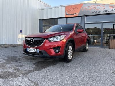 une Mazda CX-5 rouge garée devant un immeuble