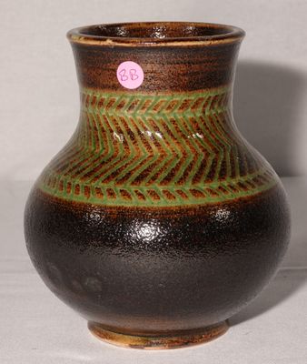 un vase marron et vert posé sur une surface blanche