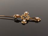 a close up of a gold necklace with pearls on a black surface