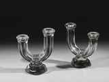 une paire de bougeoirs en verre transparent posés sur une surface blanche
