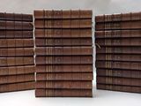 plusieurs livres marron empilés les uns sur les autres sur une surface blanche
