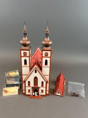 une petite maison de poupées avec un toit rouge et deux tours