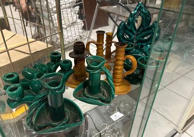 une vitrine en verre remplie de vases verts et de bougies