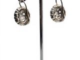 pair of silver plated earrings on a stand on a white background