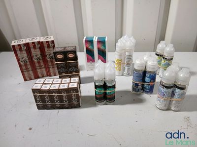 plusieurs bouteilles de liquide posées sur une table à côté d'un paquet de cigarettes