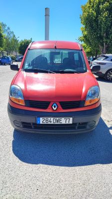 une voiture rouge garée sur un parking, avec d'autres voitures en arrière-plan