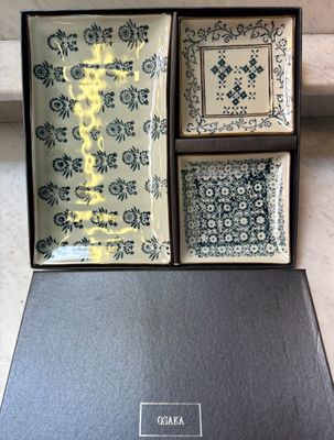 three square plates in a black box with blue and white designs