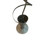a metal sculpture of a bird sitting on top of a vase