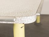 a close up of a table with yellow legs and a white table top
