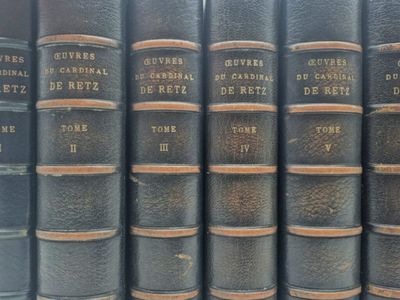 several old books are lined up on a shelf in a library