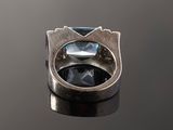 a close up of a silver ring with a blue topaz stone
