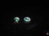 pair of green tourmaline gems on a black surface