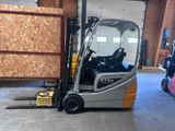 un chariot élévateur dans un entrepôt, avec une palette au premier plan