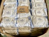 une boîte en carton remplie de paquets de savon et une main tenant un gant vert